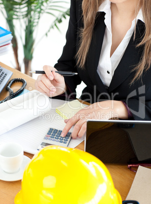 Busy businesswoman working in her office with a calculator