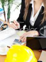 Busy businesswoman working in her office with a calculator