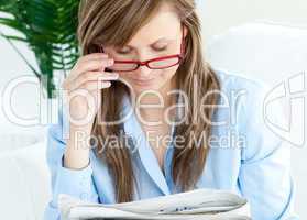 Enthusiastic woman with glasses reading a newspaper