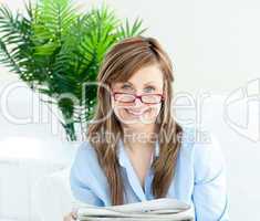 Glowing woman with glasses reading newspaper
