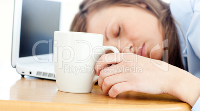 Slumbery woman sleeping on table in office