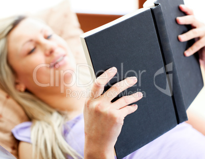 Glowing woman lies on sofa and reading a book