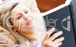 Radiant woman lies on sofa and reading a book