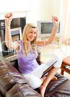 Cheering woman sitting on sofa and working