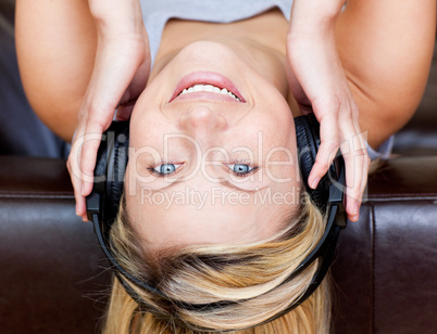 Delighted woman lies on a sofa and listen music