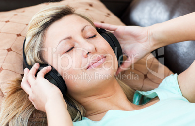 Relaxed woman lies on a sofa and listen music