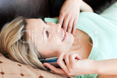 Laughing woman lies on sofa and phoning