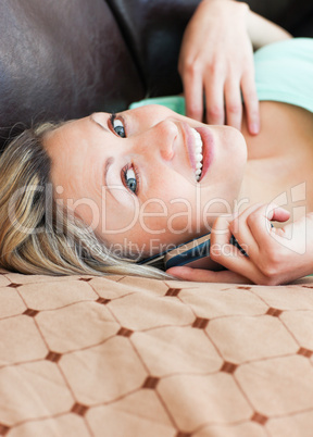 Joyful woman lies on sofa and phoning