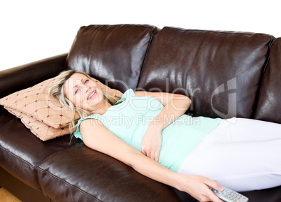 Unstressed woman lies on sofa and watches TV