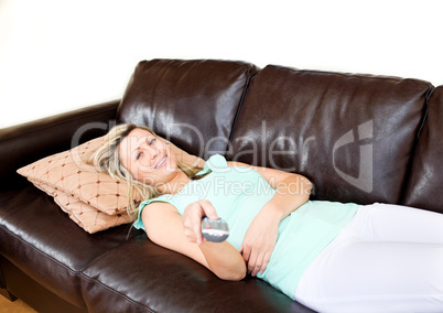 Slack woman lies on sofa and watches TV
