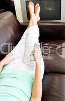 Relaxed woman lies on sofa and watches TV