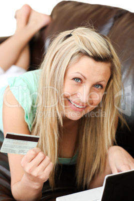 Sweet woman lies on sofa and works at laptop