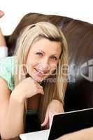 Cute woman lies on sofa and works at laptop