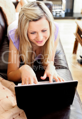 Attractive woman lies on sofa and working