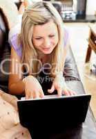 Attractive woman lies on sofa and working
