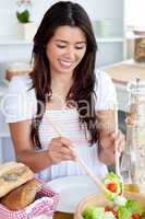 Young female woman preparing salad in kitchen