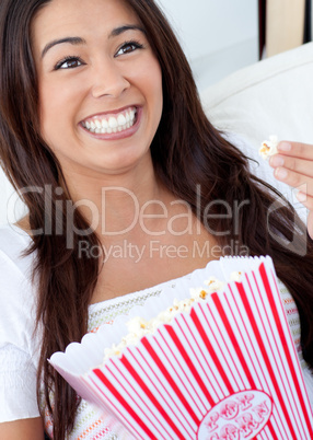 Woman sitting on sofa and eating popcorn