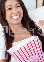 Woman sitting on sofa and eating popcorn