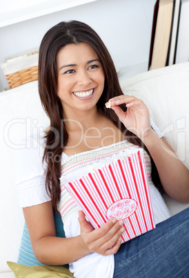 Woman sitting on sofa and eating popcorn