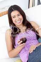 Smiling woman sitting on sofa and drinking