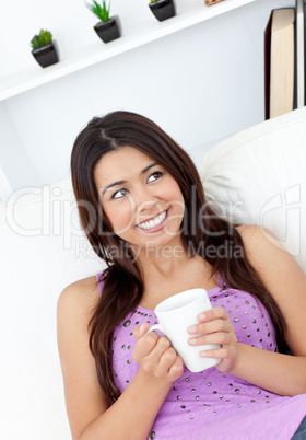 Glad woman sitting on sofa and drinking