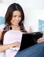 Joyful woman sitting on sofa in front of her laptop