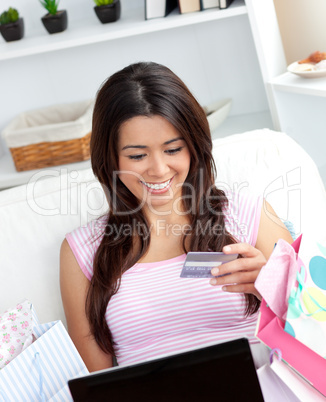 Smiling woman sitting on sofa in front of her laptop