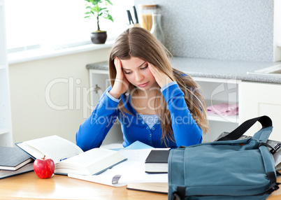 Happy female teenager studying in the kitchen