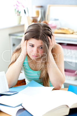 Stressed female teenager studying in the kitchen