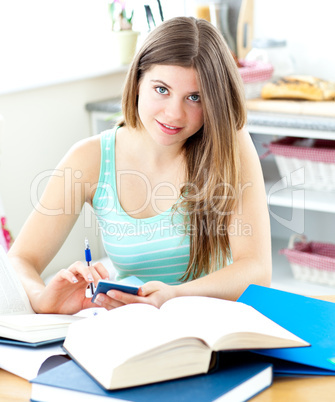 Smiling female teenager studying in the kitchen