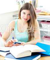 Smiling female teenager studying in the kitchen