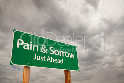 Pain and Sorrow Green Road Sign Over Storm Clouds