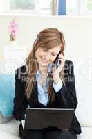 Glowing businesswoman using her phone and laptop