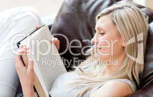 Charming woman reading a book sitting on a sofa