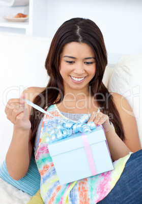 Joyful woman holding a present sitting on a sofa