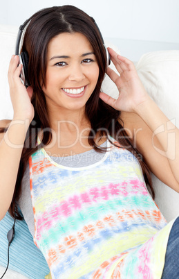 Jolly woman with headphones on lying on a sofa