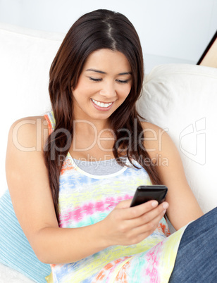 Cheerful woman sending a text sitting on a sofa