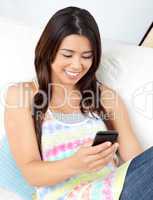 Cheerful woman sending a text sitting on a sofa