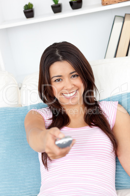 Delighted woman looking at the camera holding a remote