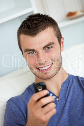 Cheerful man writing a message sitting on a couch