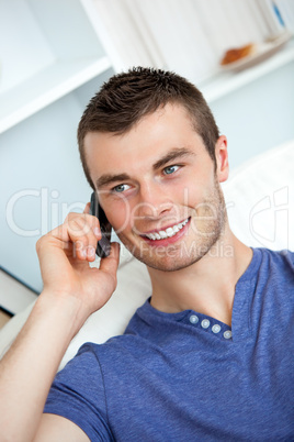 Attractive man sitting on sofa and talking on phone