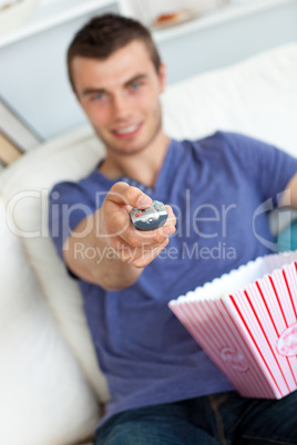 Smiling man is relaxing in the living-room with popcorn