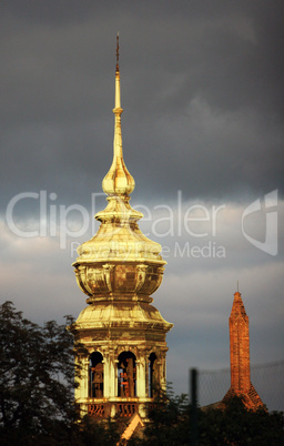 Golden tower of the church in the cloudy sky