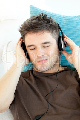 Attractive young man listening to music lying on a sofa