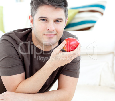 Jolly man holding a red apple lying on the floor