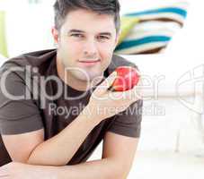 Jolly man holding a red apple lying on the floor