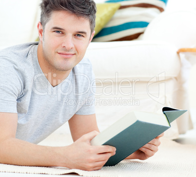 Happy young man looking at the camera holding a book