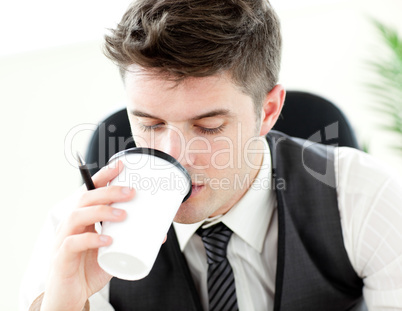 Young businessman drinking coffee in the office