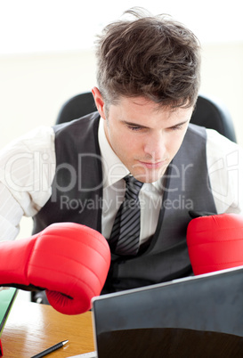 Ambitious businessman wearing boxing gloves in the office