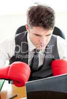 Ambitious businessman wearing boxing gloves in the office